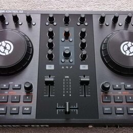 Černý DJ kontrolér s nápisem TRAKTOR KONTROL S2 v levém horním rohu. Zařízení má dva velké jog-kola s bílým logem, zahlreichetočítka a posuvníky. Pov…