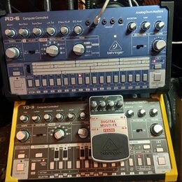 Dvě elektronické hudební zařízení značky behringer. Horní přístroj je modré barvy s nápisy RD-6 Computer Controlled Analog Drum Machine. Dolní přístr…