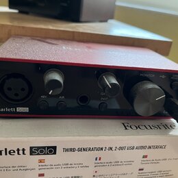Červená USB audio rozhraní s nápisy Scarlett Solo a Focusrite. Na předním panelu jsou dva ovratové knofíky, jeden velký kruhový knofík MONITOR a vstu…