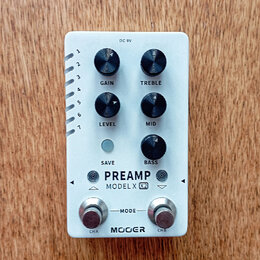 Bílý efekt pedál s nápisy PREAMP a MODEL X X2. Zařízení má pět černých otočných ovladačů s popisky GAIN, TREBLE, LEVEL, MID a BASS, jedno tlačítko SA…