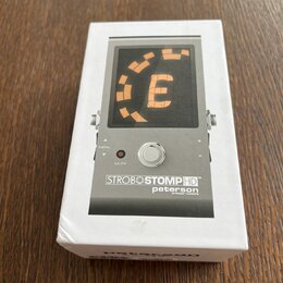 Bílá krabice s obrázkem stroboskopického ladicího pedálu. Na zařízení je vidět displej s oranžovým symbolem a nápisy MENU, MUTE a STROBOSTOMPHD™ pete…
