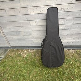 Černý poloměký pouzdro (gig bag) na kytaru. Povrch je z černé textilie s viditelným zipem podél celé délky a menším kapsáři v dolní části. Na pouzdře…