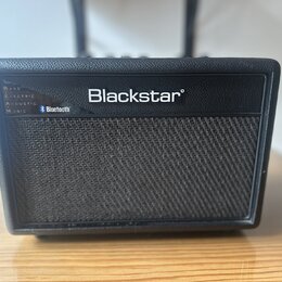 Černý kytarový kombozesilovač s texturovaným povrchem a předním mřížkovým krytem. Na horní části je bílý nápis Blackstar® a vlevo seznam kategorií BA…