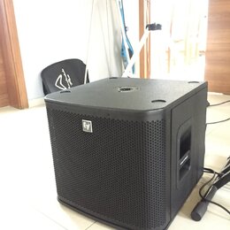 Černý subwoofer s hranatým tvarem a přední kovovou mřížkou. Na mřížce je umístěno bílé logo "EV". Povrch je v matném provedení, horní strana obsahuje…