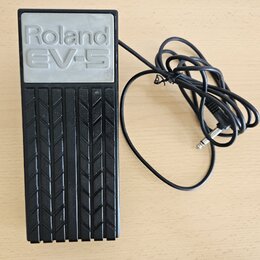 Černý expresní pedál s gumovou protiskluzovou texturou v podobě ševronů. Na horní části je šedý panel s vyraženým nápisem Roland EV-5. K zařízení ved…