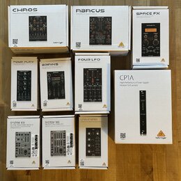 Fotografie zobrazuje deset bílých krabic s moduly pro Eurorack od značky behringer. Na krabicích jsou uvedeny názvy modelů: CHAOS, ABACUS, SPACE FX,…