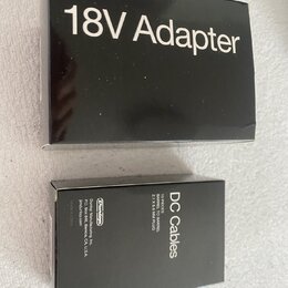 Černá krabička s bílým nápisem 18V Adapter. Vedle ní je menší černá krabička s bílým nápisem DC Cables a textem Dunlop Manufacturing, Inc. P.O. Box 6…