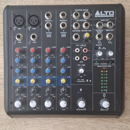 Šedý mixážní pult značky ALTO PROFESSIONAL. Na panelu jsou čtyři vstupní kanály označené CH1 až CH4, sekce BLUETOOTH a MAIN OUT. Jsou zde viditelné n…