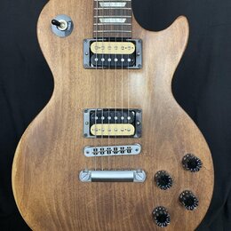 Elektrická kytara s hnědým dřevěným povrchem a dvěma humbuckery. Na přepínači je nápis TREBLE. Kytara má čtyři černé oválné knofíky a stříbrný most s…