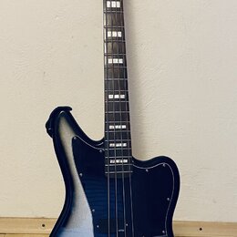 Elektrická basová kytara s offsetovým tvarem korpusu v černo-stříbrném přechodovém lakování. Na hlavě hmatníku je bílý nápis Squier JAGUAR BASS. Nást…