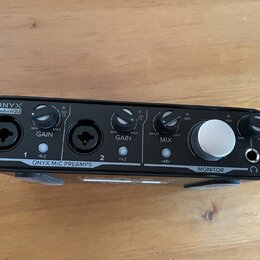 Černý zvukový interface s nápisy ONYX Producer 2-2 a ONYX MIC PREAMPS. Na horní straně jsou dva vstupy, dva ovratidla GAIN s označením MIN a MAX, ovr…