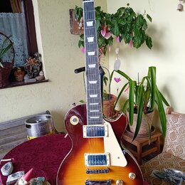 Elektrická kytara typu Les Paul s barevným přechodem od žluté přes oranžovou k červené. Na hlavě hmatníku je nápis "Les Paul Model" a logo značky. Ky…