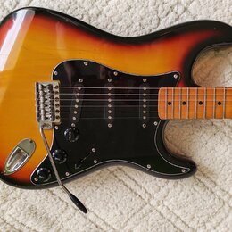 Elektrická kytara s trupem v barevnosti sunburst a černým pickguardem. Na kytare jsou tři snímače typu single-coil, chromovaný most s páčkou a tři ov…
