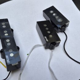 Tři černé elektrické snímače kytary s viditelnými kulatými magnety. Na dvou z nich je bílý nápis MEHTNUI TE. Snímače mají připojené vodiče v barvách…