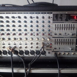 Stříbrošedý napájený mixážní pult v černém kufrovém pouzdře. Na předním panelu jsou nápisy BEHRINGER EUROPOWER, 2 X 250-WATTS STEREO POWERED MIXER WI…