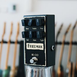 Černý kytarový efekt pedál s opotřebovými stopami v podobě odřenin na hranách. Na horní části jsou šest černých otočných oválů s popisky Bass, Treble…