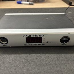 Stříbrno-černý externí zvukový interface s digitálním displejem. Na předním panelu je nápis AXON AX 50 USB a pod displejem označení TERRATEC PRODUCER…