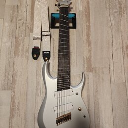 Stříbrná elektrická kytara s dvojsečným výřezem korpusu a šesti strunami. Na hlavě je viditelný nápis Ibanez. Kytara má dva humbuckery, zlatý most a…
