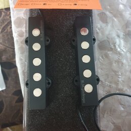 Dva černé snímače pro elektrickou kytaru umístěné v plastovém obalu na černém molitanu. Oba snímače mají pět bílých pólů a nápis R.M.pickups. V dolní…