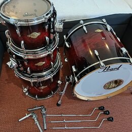 Sada červeně stínovaných bubnů značky Pearl v lesklém povrchu s viditnou strukturou dřeva. Na korusech jsou nápisy Masters a na basovém bubnu logo Pe…