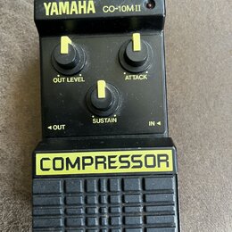 Černý kompresor s nápisem YAMAHA CO-10M.II v horní části a žlutým nápisem COMPRESSOR na spodním panelu. Zařízení má tři černé oválné knoflíky s žlutý…