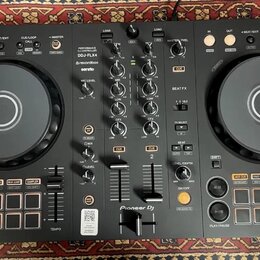Černý DJ kontrolér s dvěma jog-koly a centrálním mixážním sekcí. Na přístroji jsou viditelné nápisy PERFORMANCE DJ CONTROLLER, DDJ-FLX4, rekordbox a…