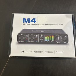 Fotografie znázorňuje krabici od USB audio rozhraní. Na krabici je velký modrý nápis M4 a text 4-in / 4-out USB audio interface with studio-quality s…