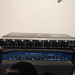 Stříbrné rackové zařízení s nápisem ULTRAGAIN PRO-8 DIGITAL obsahuje osm kanálů s XLR vstupy a ovládacími knoflíky. V pravé části jsou přepínače PHAN…