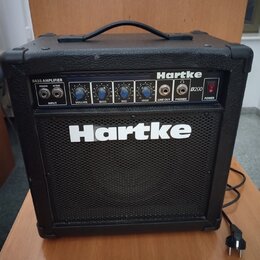 Černý basový kombozesilovač s nápisy Hartke a B200. Horní ovládací panel obsahuje vstup INPUT s přepínačem PASSIVE/ACTIVE, čtyři modré otočné ovladač…