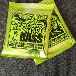 Dvě uzavřená balení basových strun v limegreenovém obalu. Na obalech je černý nápis ERNIE REGULAR BALL SLINKY BASS s rozměry 50, 70, 85, 105 a textem…