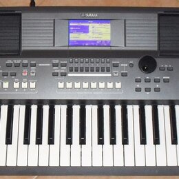 Šedý digitální klavír s nápisem YAMAHA v horní části. V pravém dolním rohu je označení modelu PSR-S570. Nástroj má vestavěný displej, dvě mřížky repr…