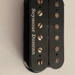 Černý humbucker snímač s dvěma řadami pólů. Na levém krytu je bílý nápis Seymour Duncan. Povrch vykazuje drobné škrábance a opotřebení, zejména u šro…