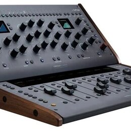 Šedý kontrolér s dřevěným bočním rámem a dvěma malými displeji. Na horním panelu je nápis CONSOLE 1 a v pravém horním rohu logo Softube. Zařízení obs…