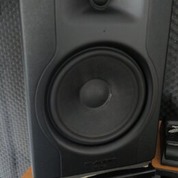 Černý studiový monitor s dvěma reproduktory umístěný na černém stojanu. V dolní části přední mřížky je vyražen nápis M-AUDIO BX. Povrch je matný, s v…