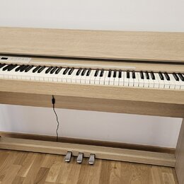 Digitální piano v dřevěném provedení světlé barvy s integrovaným stojanem a třemi pedály. Na pravém boku korpusu je viditelné logo Roland. Nástroj má…