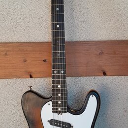 Elektrická kytara s polodupatým korpusem v barevném přechodu od žluté k černé a s bílým pickguardem. Na korpusu je viditelný nápis Jazzmaster a na hl…