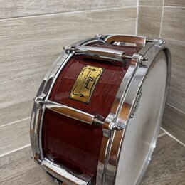 Hnědý dřevěný buben s chromovaným kováním a bílým blátcem. Na korpusu je čtvercový štítek s nápisy „Pearl“, „Master's Idea“ a „Hand-selected Mahogany…