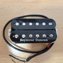 Černý humbucker s dvěma řadami šesti stříbrných pólů. Na spodní části je bílým písmem nápis Seymour Duncan. Snímač má připojený černý kabel a je umís…