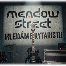 Černá elektrická kytara s tmavým hnedým hmatníkem a bílými značkami poloh. Na hlavě kytary je vidět nápis Epiphone. Kytara stojí před šedou stěnou s…