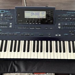 Tmavě modrý digitální klavír značky Roland, model EM-2000. Na horním panelu jsou vidět nápisy Roland, EM-2000 a Creative Keyboard. Nástroj má standar…