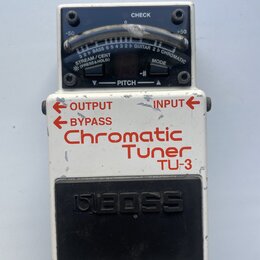 Bílý kytarový pedál s černým spínacím tlačítkem, na kterém je vyražen nápis BOSS. Na horní části je analogový ukazatel s nápisy CHECK, -50, 0, +50 a…