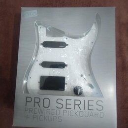 Krabice s produktem značky EMG, na které je zobrazen průhledný pickguard s třemi černými snímači. Na krabici jsou nápisy EMG, PRO SERIES a PREWIRED P…