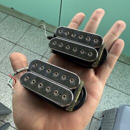 Dvě elektrické snímače typu humbucker v černé barvě s chromovanými kryty. Na krytech nejsou žádné viditelné značky ani nápisy. Snímače mají připojené…