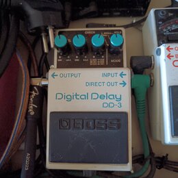 Kytarový efekt pedál Boss Digital Delay DD-3 v bílo-šedém provedení. Na horní části jsou čtyři modré ovládací knoflíky a nápisy CHECK, L 800ms HOLD,…