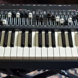 Černý syntetizátor s červenými bočními panely a bílo-černou klaviaturou. V pravém horním rohu je nápis Legend One ANALOG SYNTHESIZER. Horní panel obs…