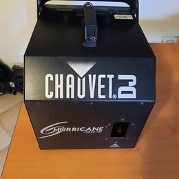 Černý generátor mlhy v kovovém hranatém provedení s úchytem. Na přední straně je bílý nápis CHAUVET DJ a níže označení HURRICANE HAZE 3D. Povrch přís…