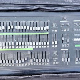 Šedý svítící panel s nápisem SIGM Studio 24 professional light controller. Zařízení obsahuje množství posuvníků, tlačítek a několik otočných ovladačů…