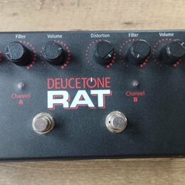 Černý efekt pedál s nápisy DEUCETONE a RAT. Horní panel obsahuje dva identické sady ovládacích prvků s popisky Distortion, Filter a Volume. Ve spodní…