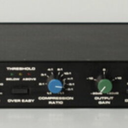 Černý rackový kompresor/limiter značky dbx, model 160XT. Přední panel obsahuje tři otočné ovladače s červeným, modrým a zeleným knoflíkem, dva přepín…