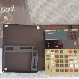 Fotografie zobrazuje elektronický hudební přístroj v hnědém kufru s nápisem Medieval a podtitulem instrumentalia electronicum. Zařízení má béžový pan…